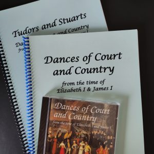 Photo of both books and CD stacked with titles visible, on a dark green desk.